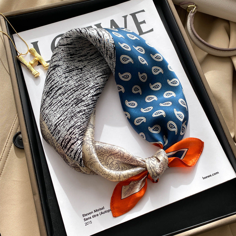 Grey and blue paisley printed square scarf with a satin sheen and hemmed edges, shown displayed