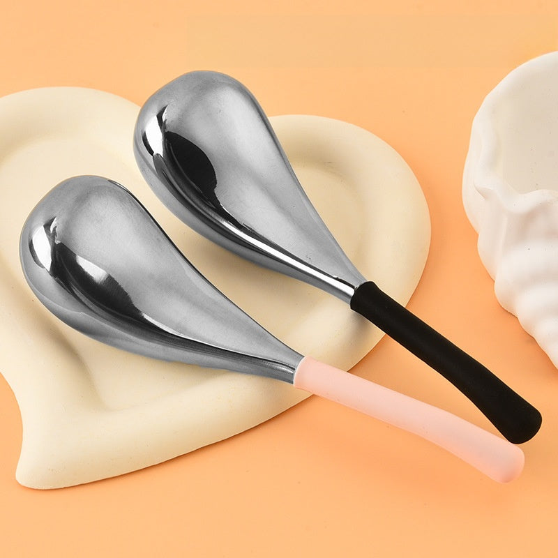 Two stainless steel facial massage globes with black and pink silicone handles on a tray