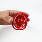 Red and gold gyro ring fidget opened into a hollow sphere between finger and thumb