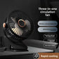Black clip fan clamped to a dark desk edge, hub light glowing behind the round grille