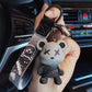 Gray color changing bear keychain held in a hand inside a car