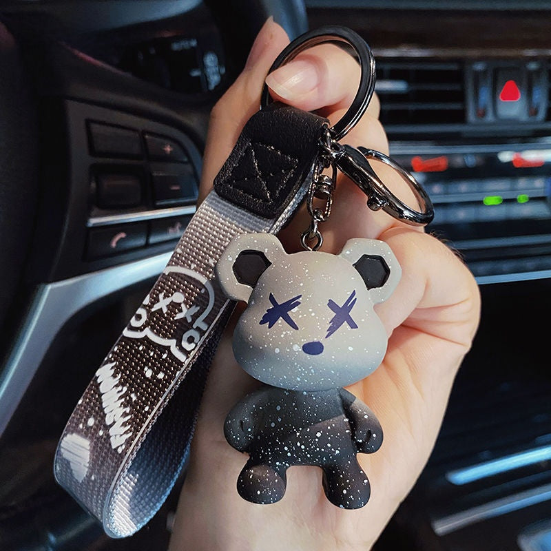 Gray color changing bear keychain held in a hand inside a car
