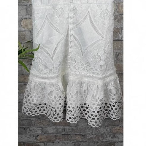 Detail of scalloped eyelet ruffle hem on the white lace short dress