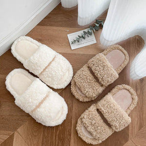 Pair of lamb plush double strap slippers with two wide bands over the foot on a wood floor