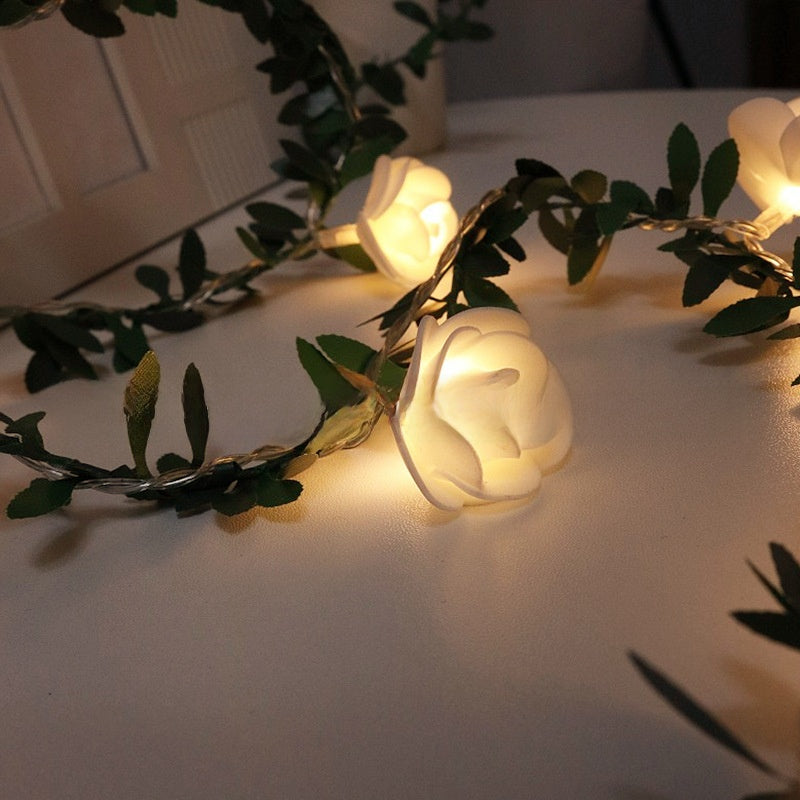 Decorative LED flower fairy string lights on a green leaf vine glowing warm, lifestyle photo
