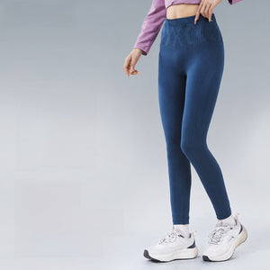 Woman in dark blue high waist compression leggings and white sneakers against a gray backdrop