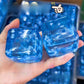Blue gel snowflake cube squishy pressed flat in a hand showing its soft slow give