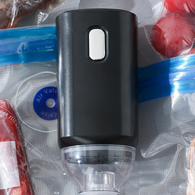 Black handheld vacuum pump over the round air valve of a reusable zip bag on the counter