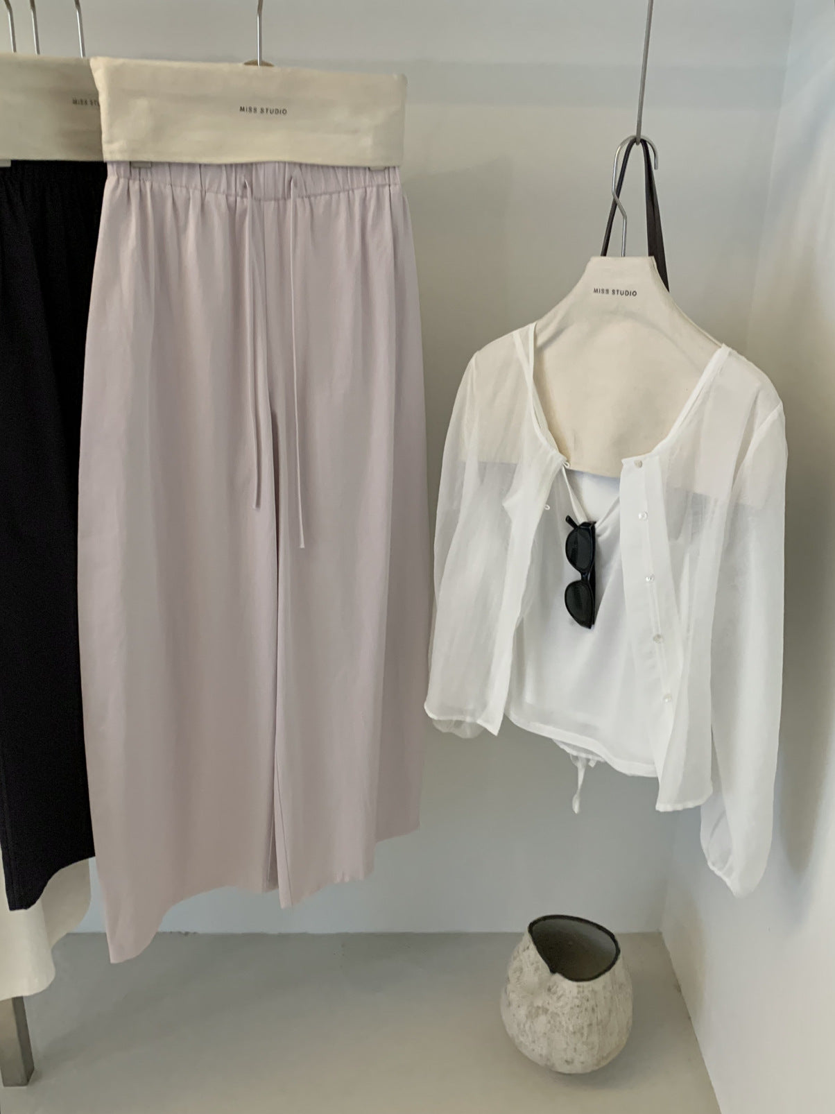 Lilac cotton wide leg trousers hung beside a sheer white shirt