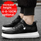 Black low-top sneakers with a Fashion tag strap and a chunky white sole, worn with black joggers on a street