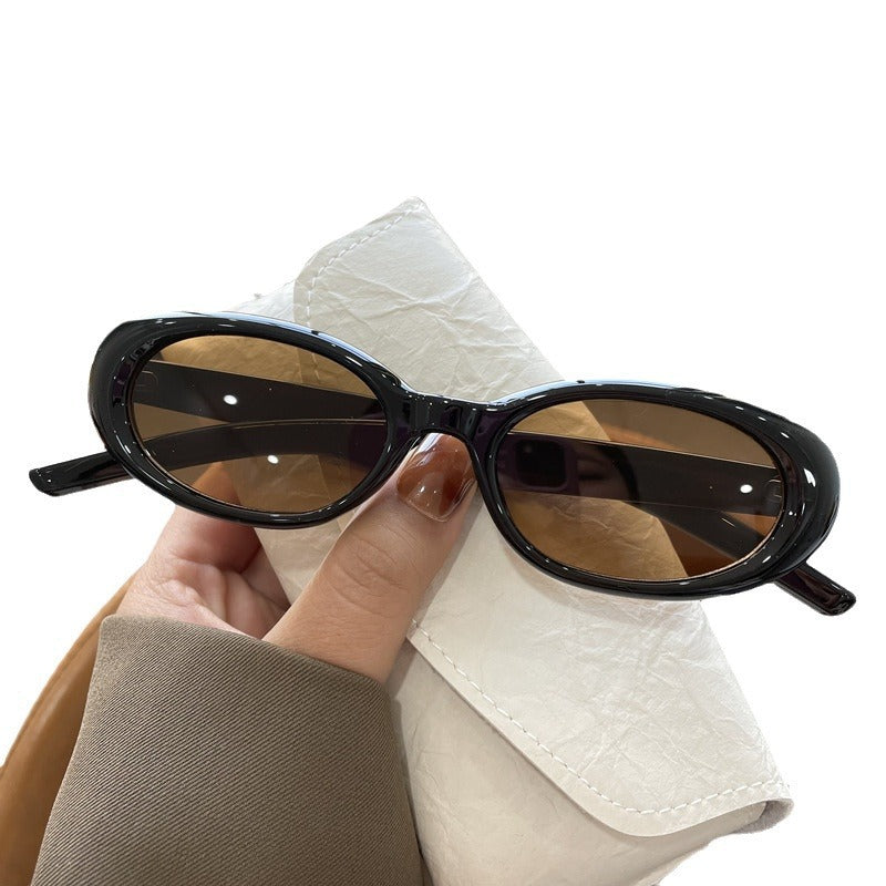 Black oval frame sunglasses with brown tea lenses on a white background with a hand and glasses case