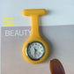 Red silicone nurse fob watch hanging from its brooch pin against a plain background