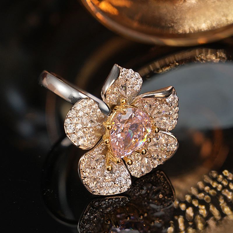 Flower design ring with gold toned pave petals around a pear cut pink simulated diamond centre stone