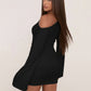 Back view of a black mini dress with one bare shoulder, a bell sleeve and a long tail of fabric at the hip