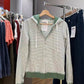 Green striped zip-up hoodie on a hanger at a clothing rack with a hang tag