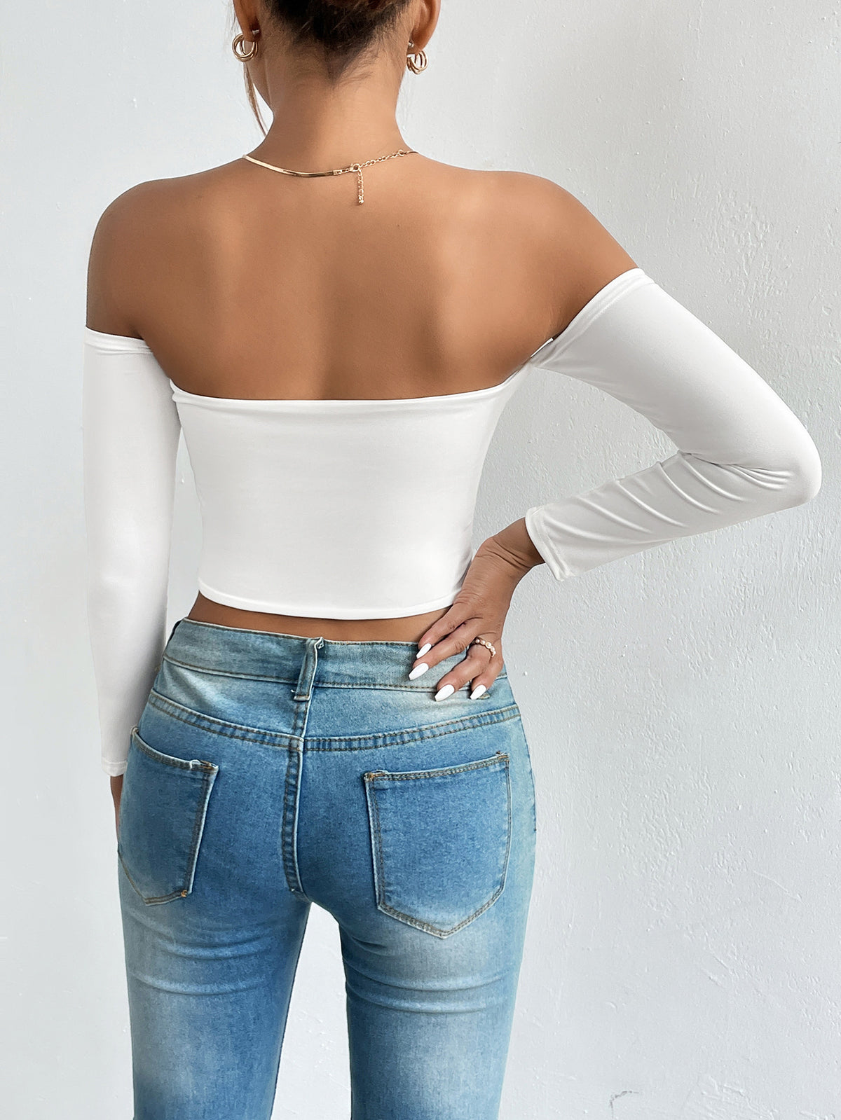 Side view of a white off shoulder long sleeve crop top showing the slim fit and cropped length