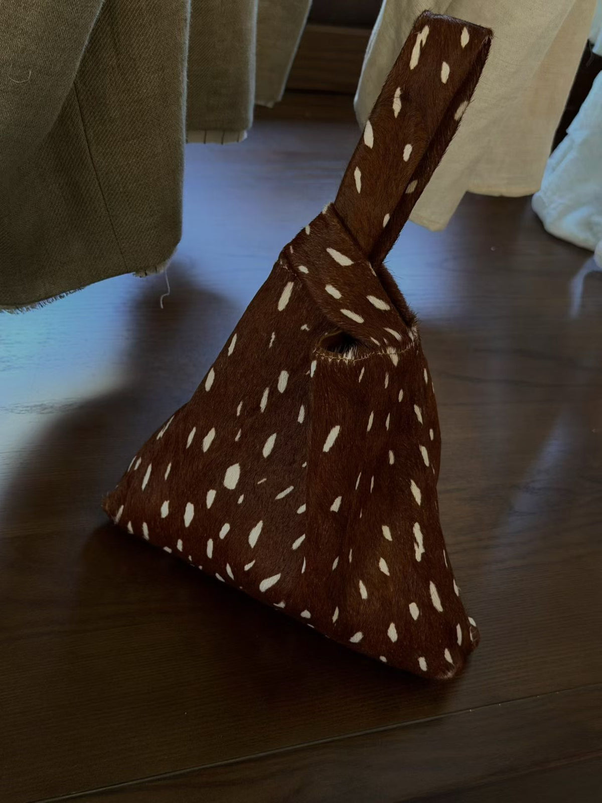 Brown triangle pouch bag with cream spots and a looped handle on a wooden table, option Brown Spots