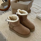 Chestnut platform ankle boots with folded shearling cuffs and small back bows on a cream rug beside a box