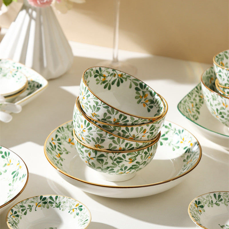 Stacked green leaf porcelain rice bowls beside a matching deep plate