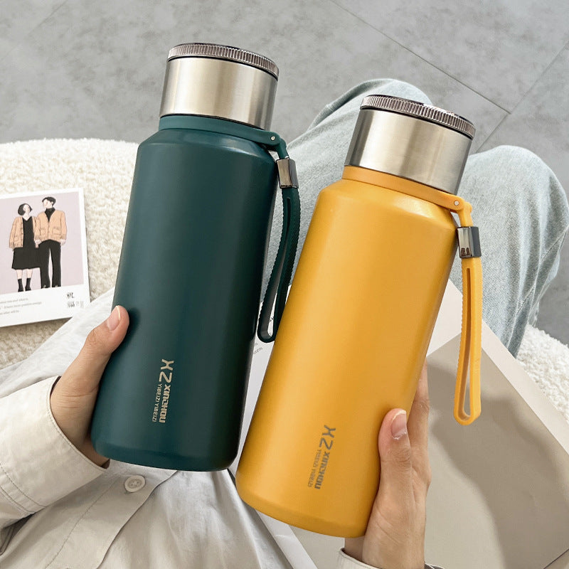 Dark green and mustard yellow insulated steel flasks with wrist straps held in two hands