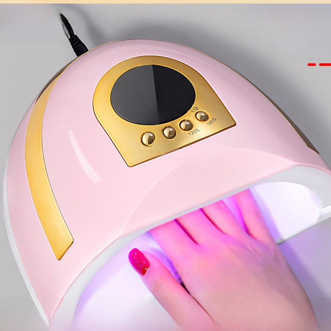 Pink nail lamp with gold trim curing a painted fingernail under red light, pink with UK plug option