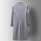 Back of a grey long coat on a hanger showing the centre back slit and three buttons at the cuff