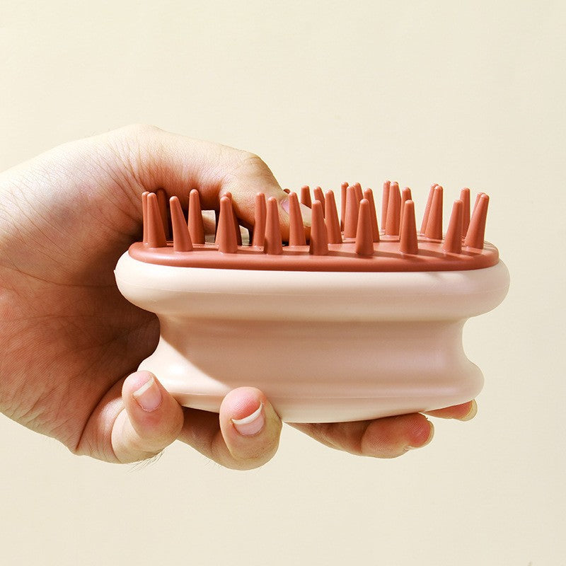Cream and rust silicone scalp shampoo brush held in a hand showing the bristles
