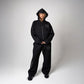 Black option photo of a woman in a black zip hoodie with hood up and wide leg trousers, size S