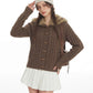Woman wearing the coffee brown cable knit cardigan with wooden toggles and fur trimmed hood, hand raised to a beanie