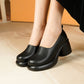 Black leather slip-on platform block heel shoes worn with a black skirt on a cream rug