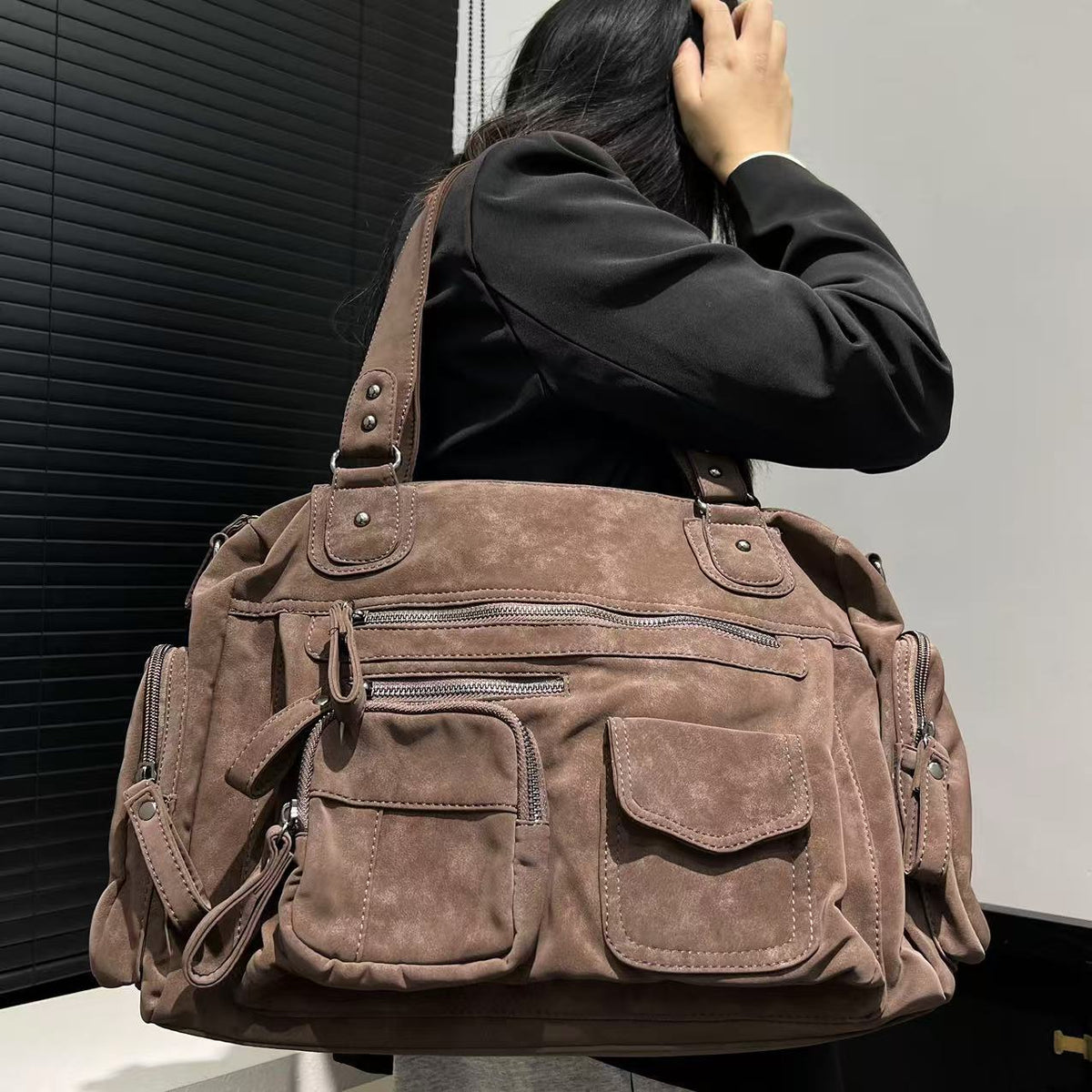 Large brown multi-pocket shoulder bag worn on the shoulder with zip pockets on the front and both ends
