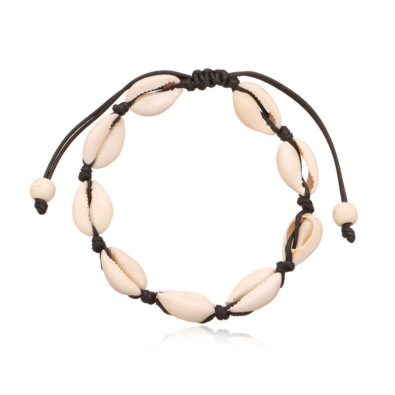 Black cord cowrie shell anklet laid flat, showing shells held by knots along the whole length