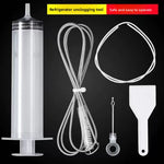 Syringe, white tube, wire brush, drain plug pin and ice scraper laid out on a black background