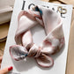Pink floral printed square scarf with a satin sheen and hemmed edges, shown displayed and knotted