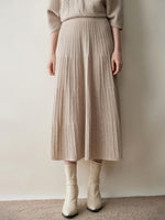 Woman in an oatmeal beige ribbed knit tiered midi skirt with cream ankle boots, front view