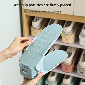 Single green plastic adjustable shoe rack holding a pair of shoes stacked to save space