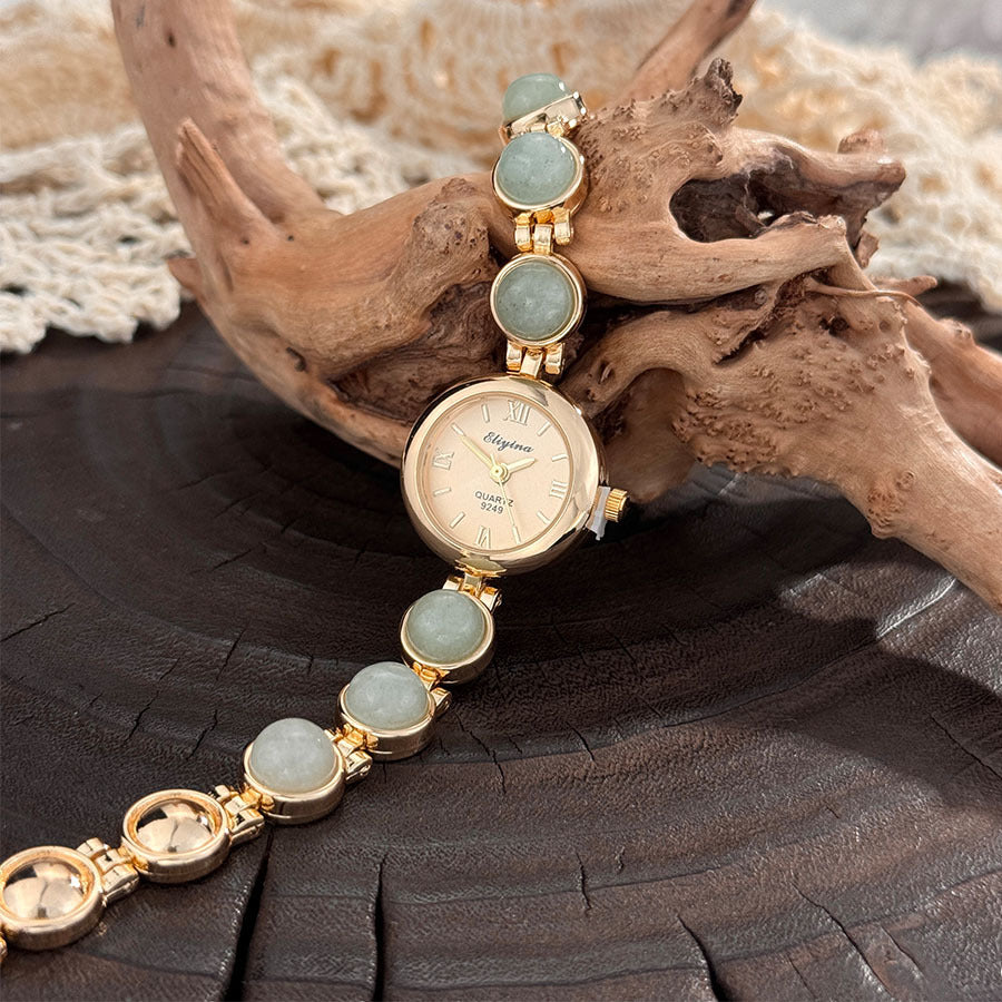 Small round gold dial quartz watch framed by round stone beads on the wrist