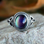 Silver tone mood ring with oval color changing cabochon and rope bezel front view