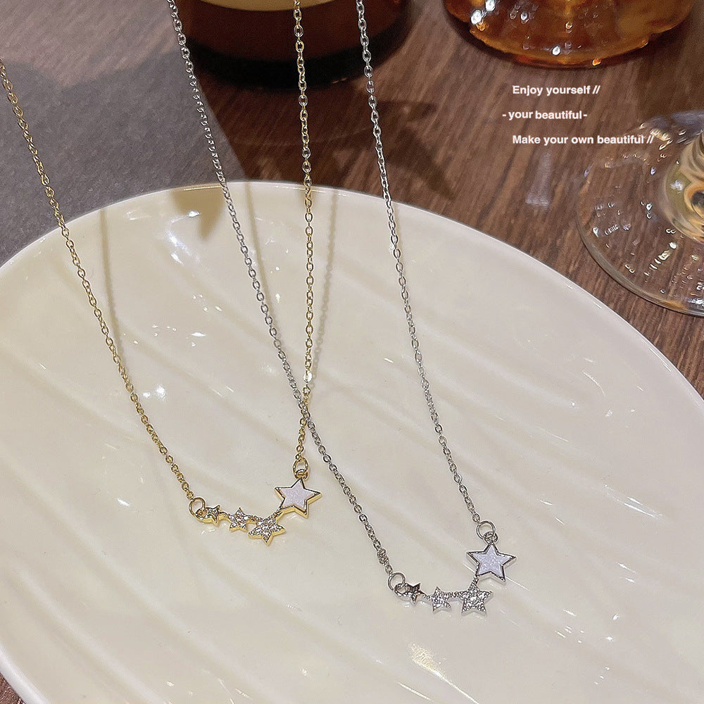 Silver tone star cluster necklace resting across the fingers of a hand