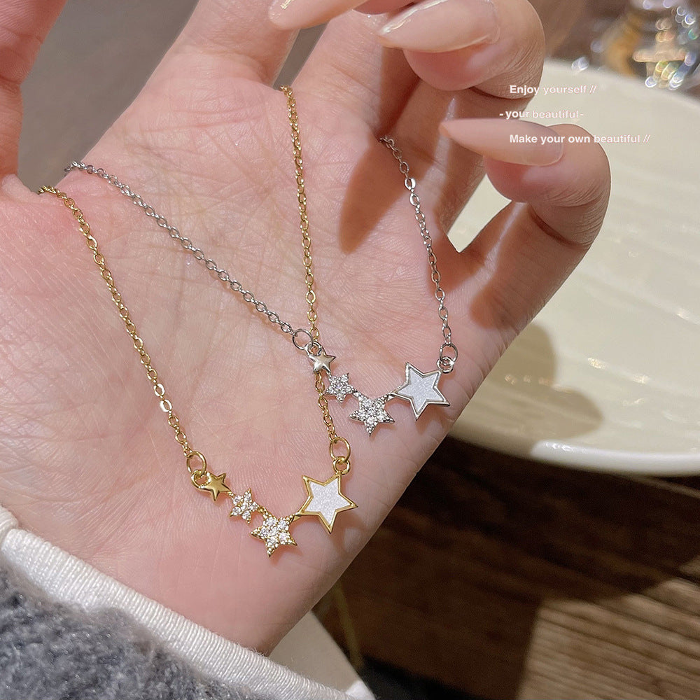 Gold tone and silver tone star cluster necklaces held in an open hand