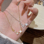 Gold tone and silver tone star cluster necklaces held in an open hand