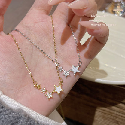 Gold tone and silver tone star cluster necklaces held in an open hand