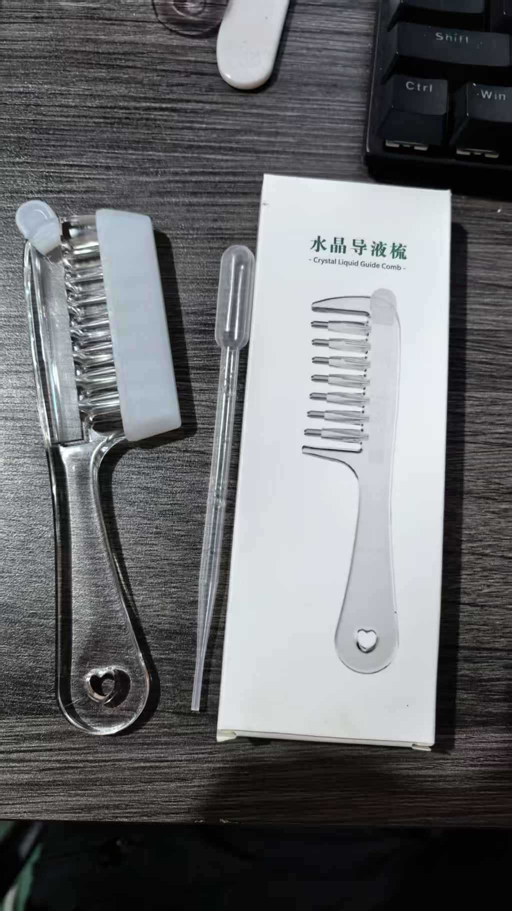 Transparent hair comb and clear dropper laid out as the complete scalp serum applicator set