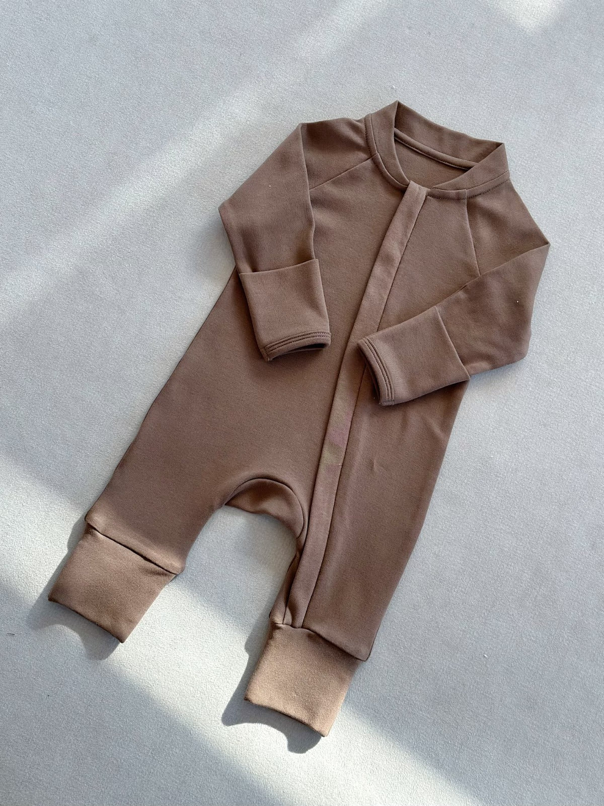 Mocha zip front baby romper laid flat on a gray floor, image of the 59 cm, 0 to 3 months size option