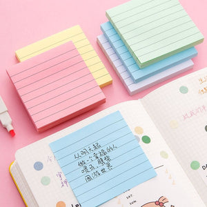 Stacks of pastel lined sticky note pads in yellow, pink, green, blue and white on a desk