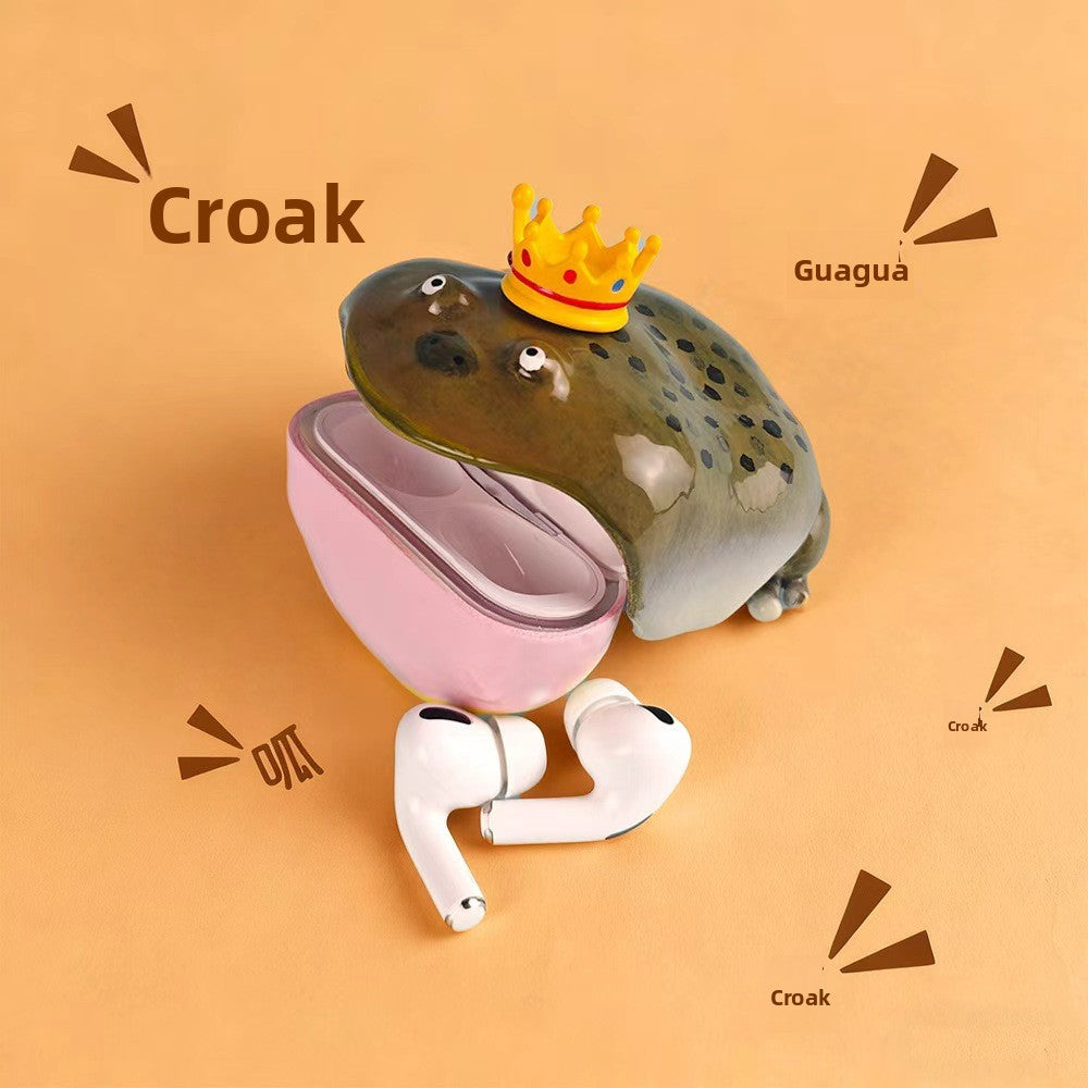 Olive frog case with a gold crown open beside a pink lower shell and a pair of AirPods Pro
