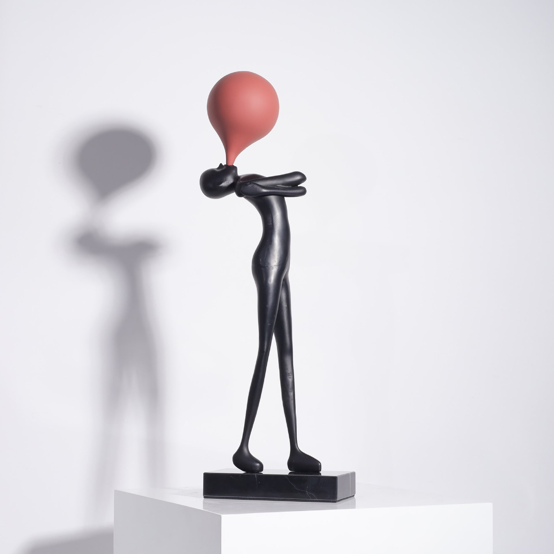 Balloon figure sculpture with a wine red balloon, slim black form standing on a polished black marble base