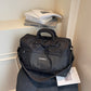 Black travel duffel with a grid front pocket, padded handles and a crossbody strap
