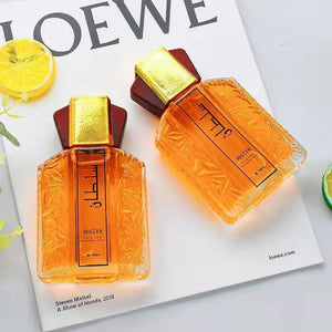 Two faceted Sultan eau de toilette bottles laid flat on a glossy magazine page with fresh lemon slices