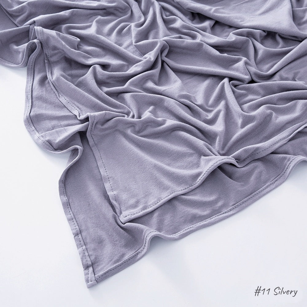 Solid tone modal cotton headscarf wrap laid in soft folds showing the fine jersey knit surface